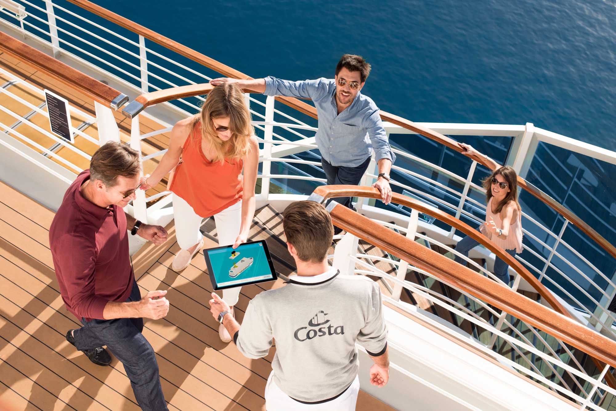 Costa Cruise Staff Presents Ship Information to Passengers A Costa Cruises staff member wearing a branded t-shirt displays ship information on a tablet to