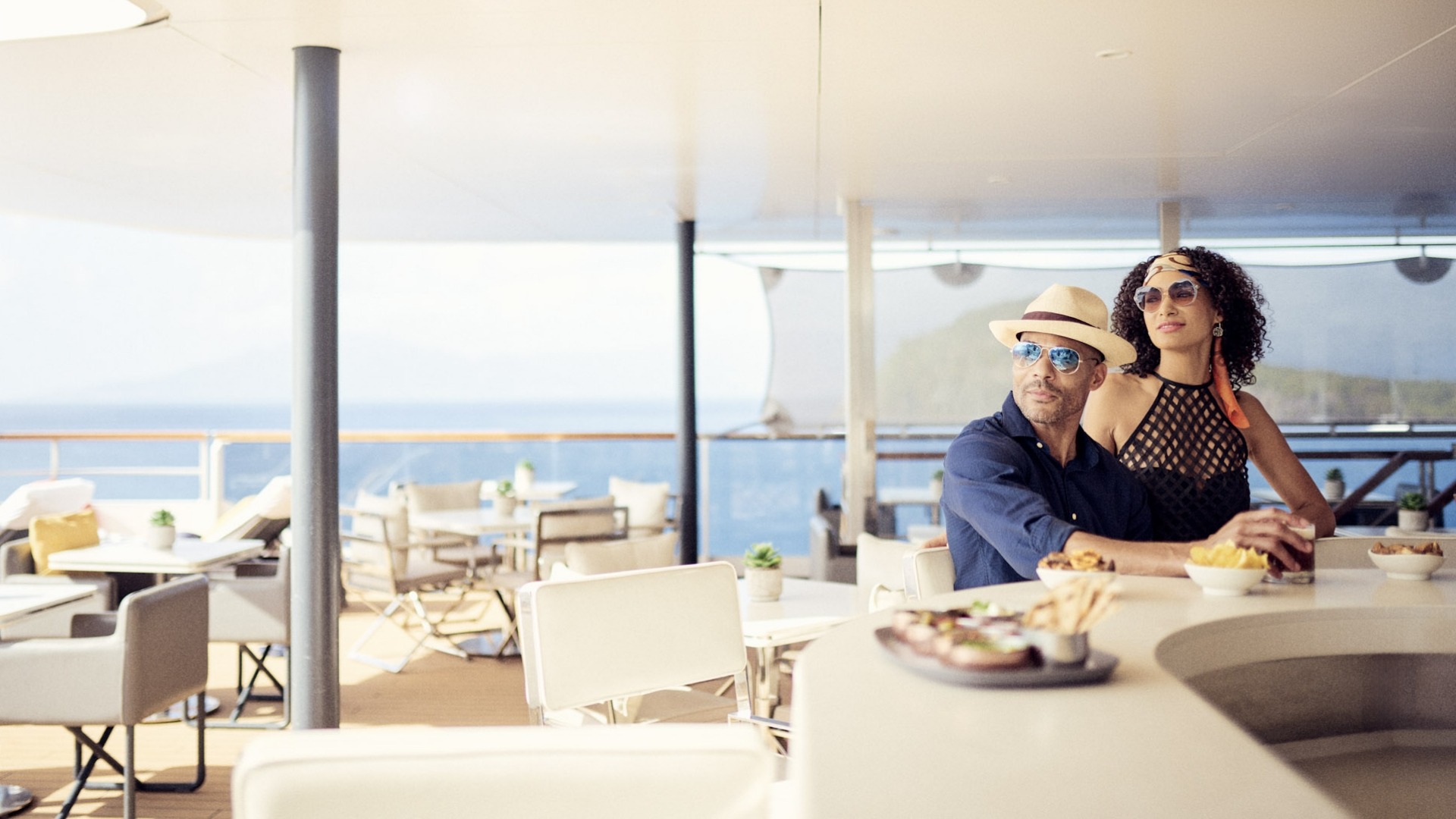 Couple Dining on Luxury Yacht Deck A well-dressed couple enjoys a meal on an expansive outdoor deck of a luxury yacht, with panoramic