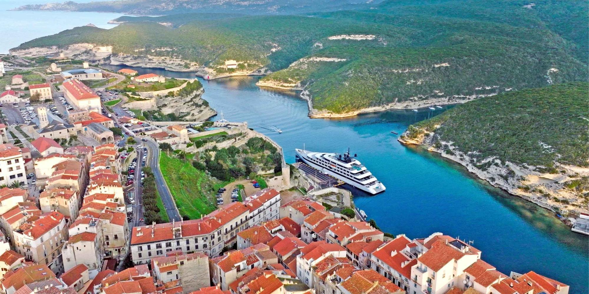Cruise Ship in Bonifacio Harbor, Corsica An aerial view of a luxury cruise ship anchored in the crystal-clear turquoise waters of Bonifacio