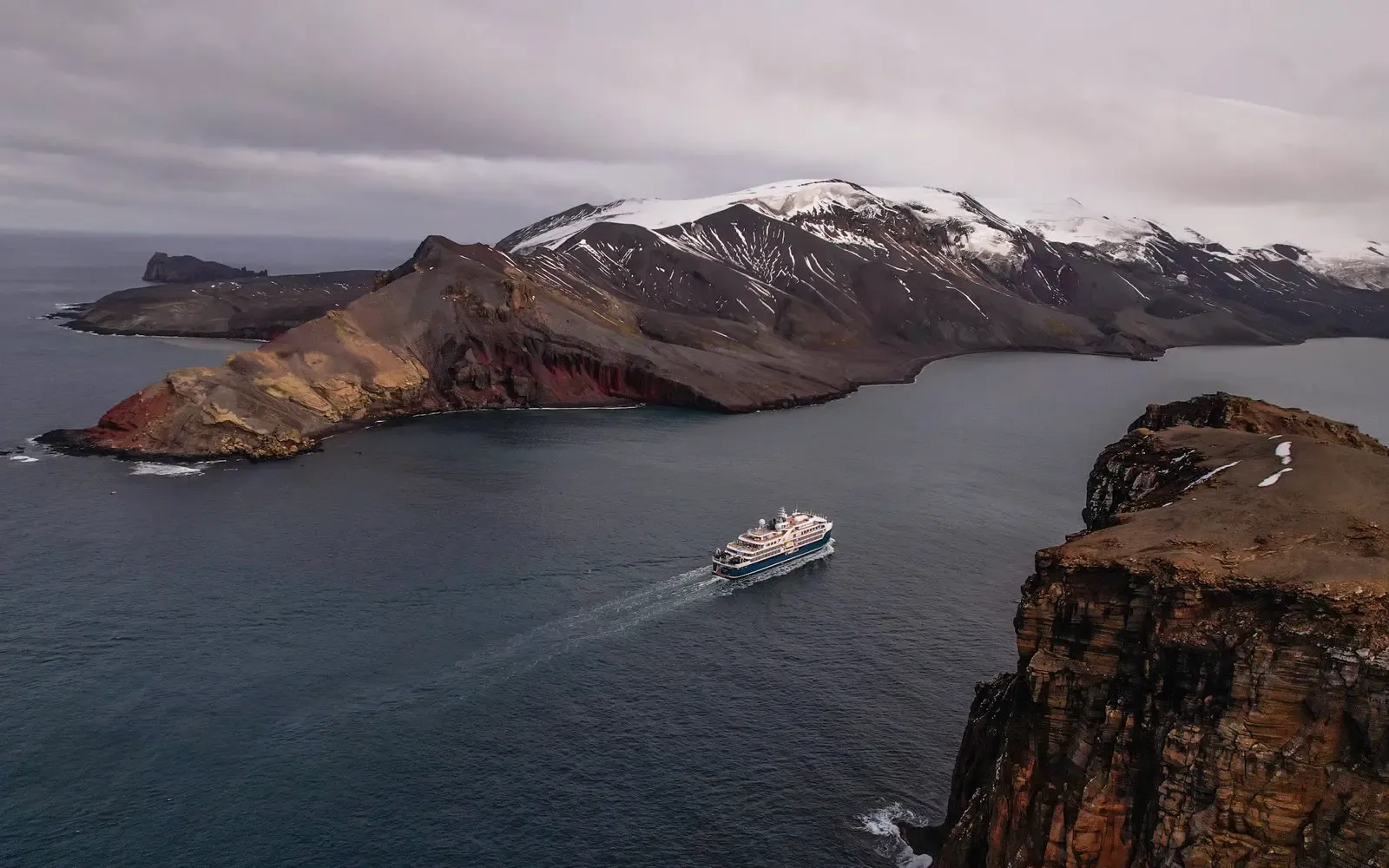 Cruise Ship in Galapagos Volcanic Landscape A small expedition cruise ship navigates turquoise waters surrounded by dramatic volcanic islands