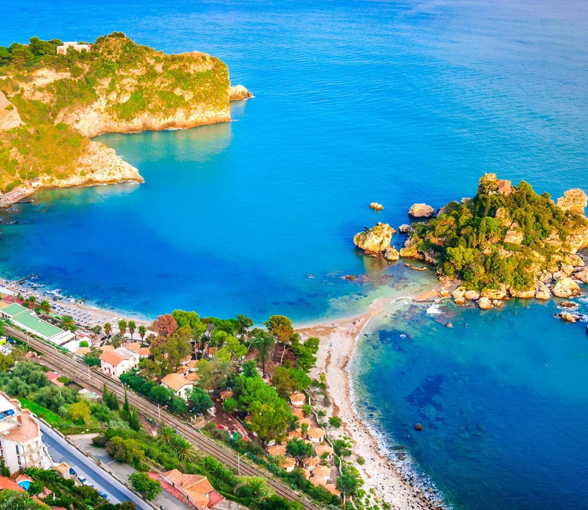 An aerial view of a picturesque Mediterranean coastal cove featuring brilliant turquoise waters