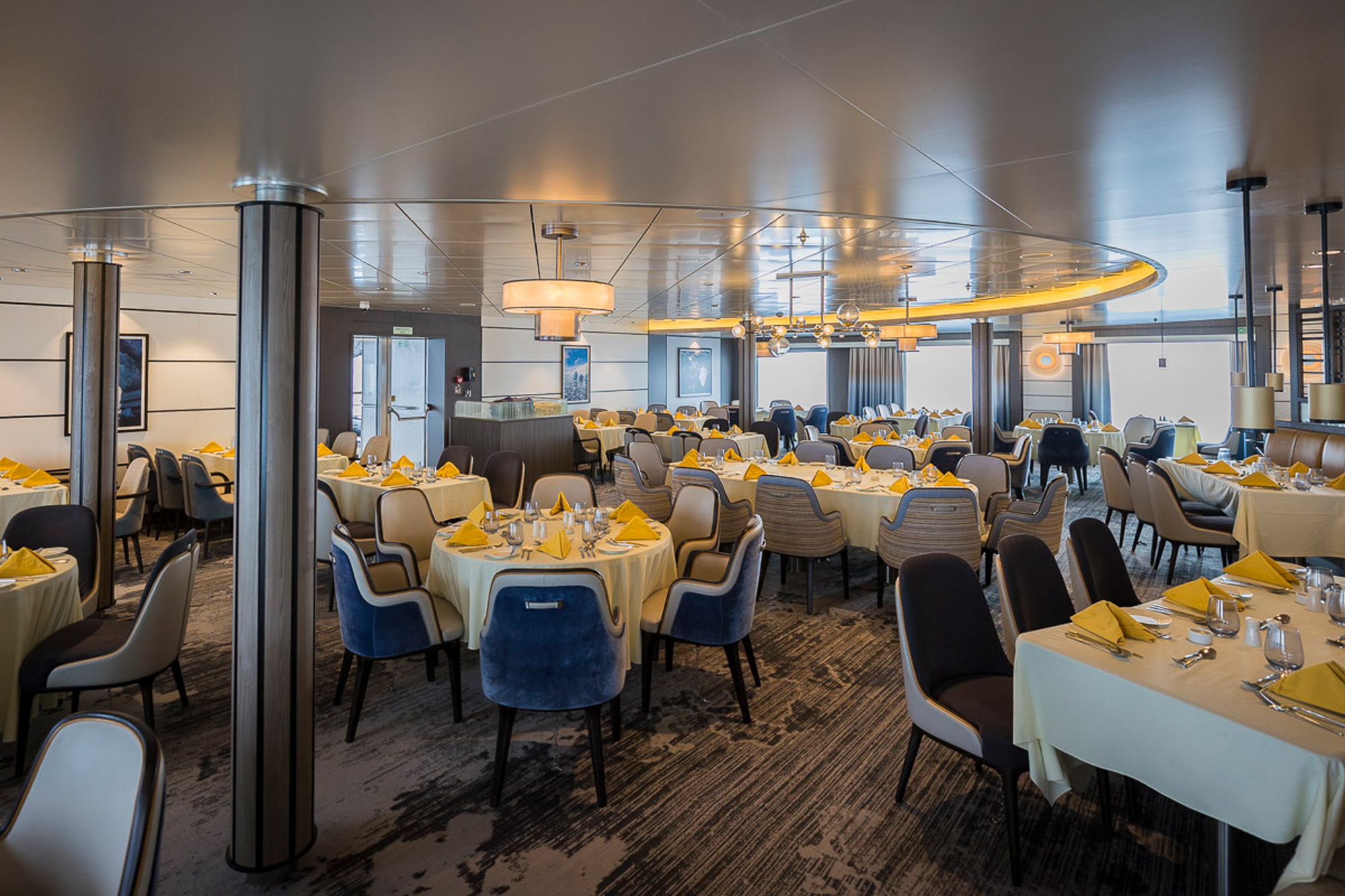 Elegant Dining Room Aboard Sylvia Earle A sophisticated ship dining room featuring round tables with cream linens and yellow napkins