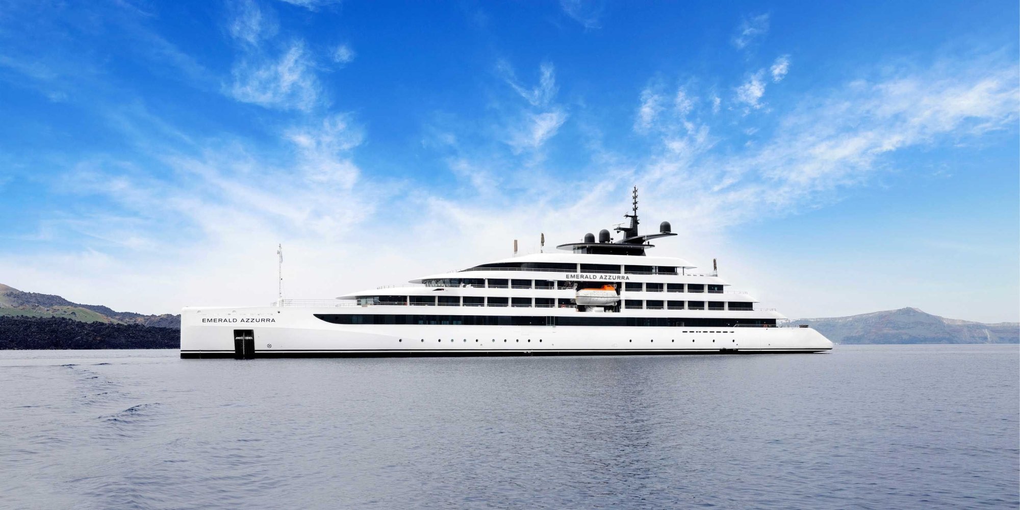 Emerald Azzurra Luxury Expedition Yacht The Emerald Azzurra, a sleek white luxury expedition yacht, anchors in clear blue waters