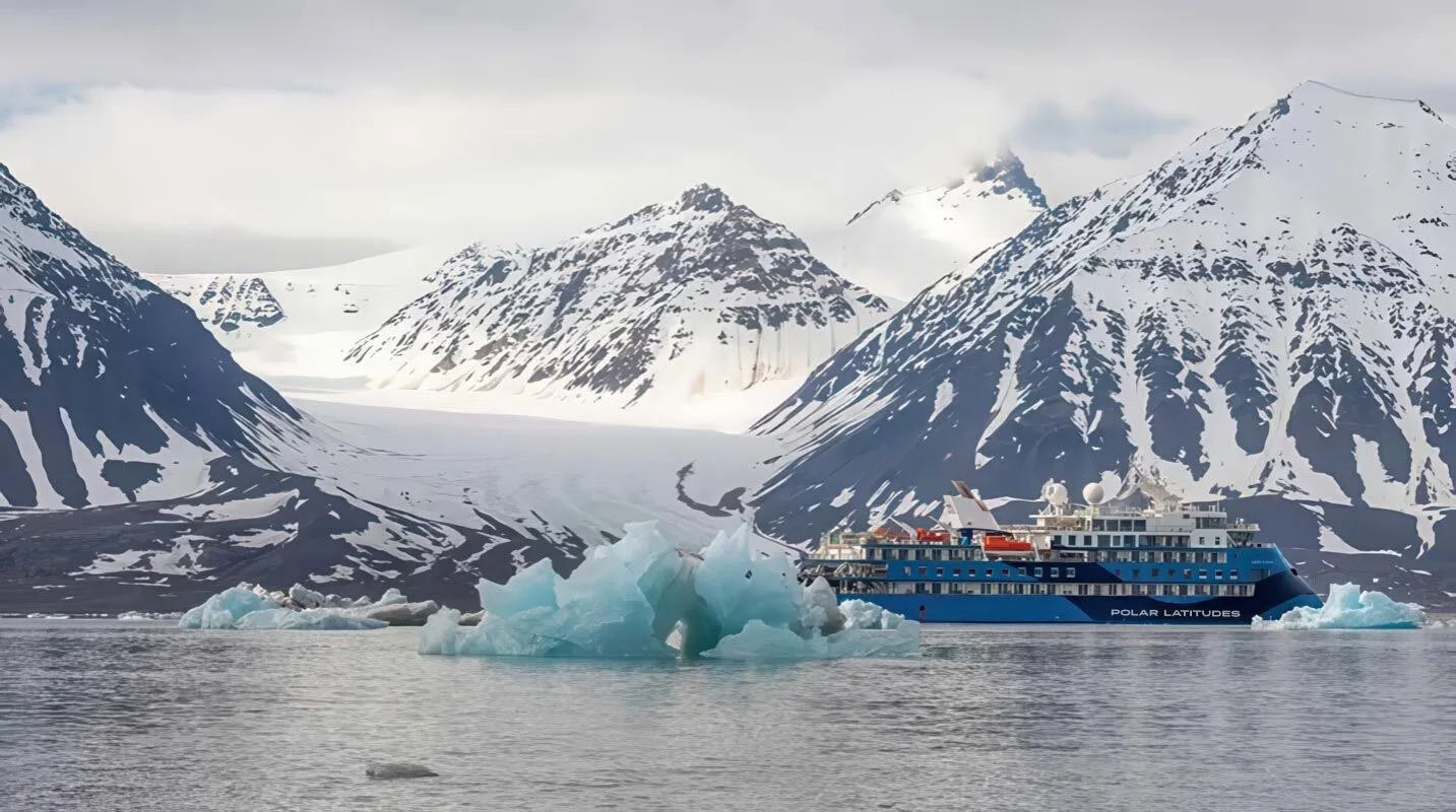 The Polar Latitudes expedition cruise ship navigates through a stunning Arctic fjord surrounded