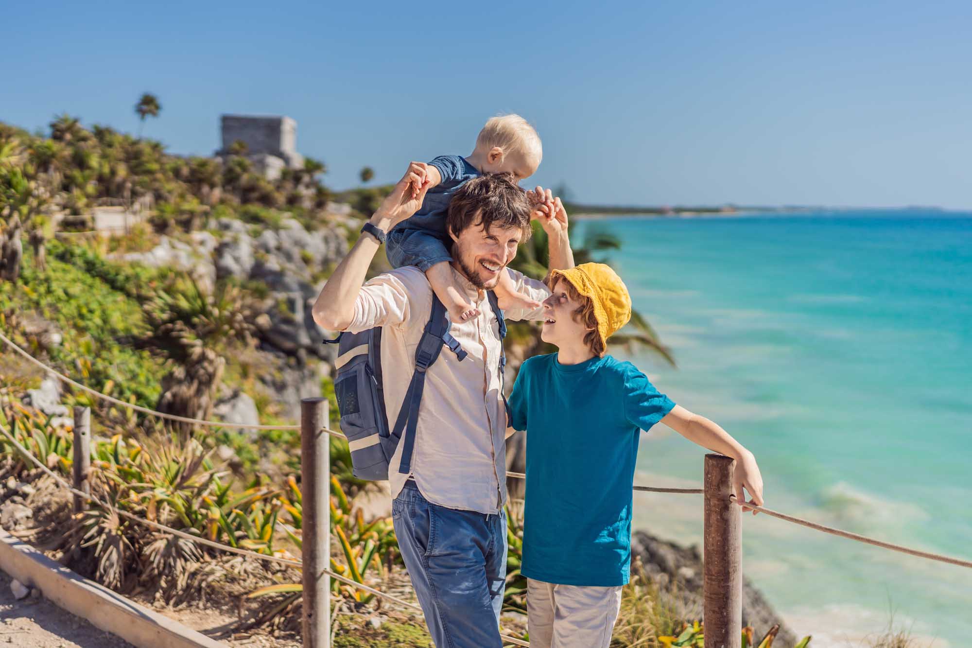 Family at Tulum Ancient Mayan Ruins Overlooking Caribbean A father with two young sons enjoys a scenic moment at the clifftop Pre-Columbian Mayan walled city