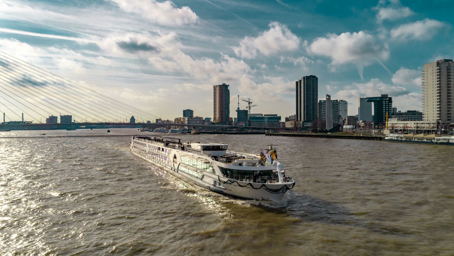 Geoffrey Chaucer River Cruise Ship in European Waterway A river cruise ship, the Geoffrey Chaucer, navigates a wide European waterway with modern high-rise