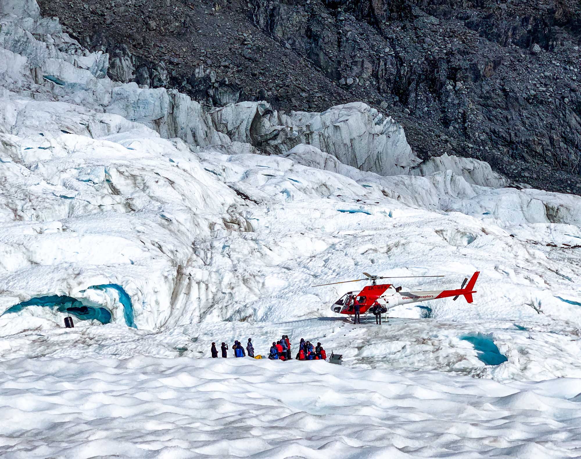 Helicopter Landing at Fox Glacier, New Zealand A red helicopter lands on the pristine white surface of Fox Glacier in New Zealand's Westland