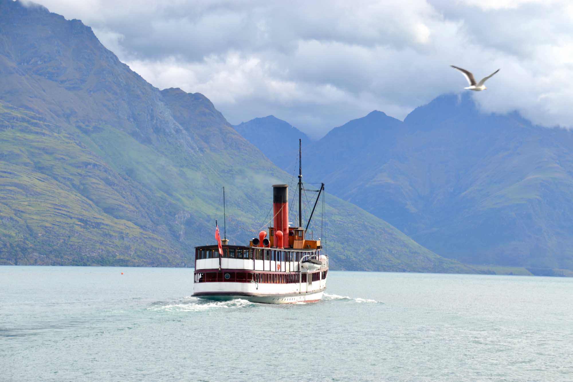Heritage Steamship on Alpine Lake A vintage red and white passenger steamship navigates the pristine waters of a mountain-ringed