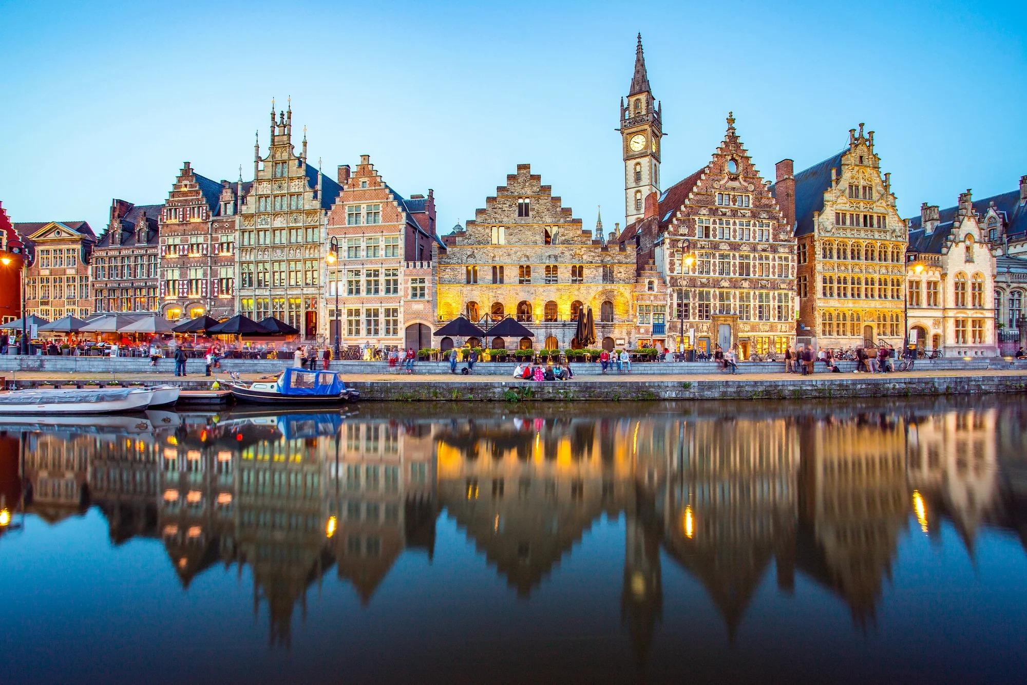 Historic Ghent Waterfront at Dusk A picturesque view of Ghent's medieval skyline reflected in calm canal waters during twilight