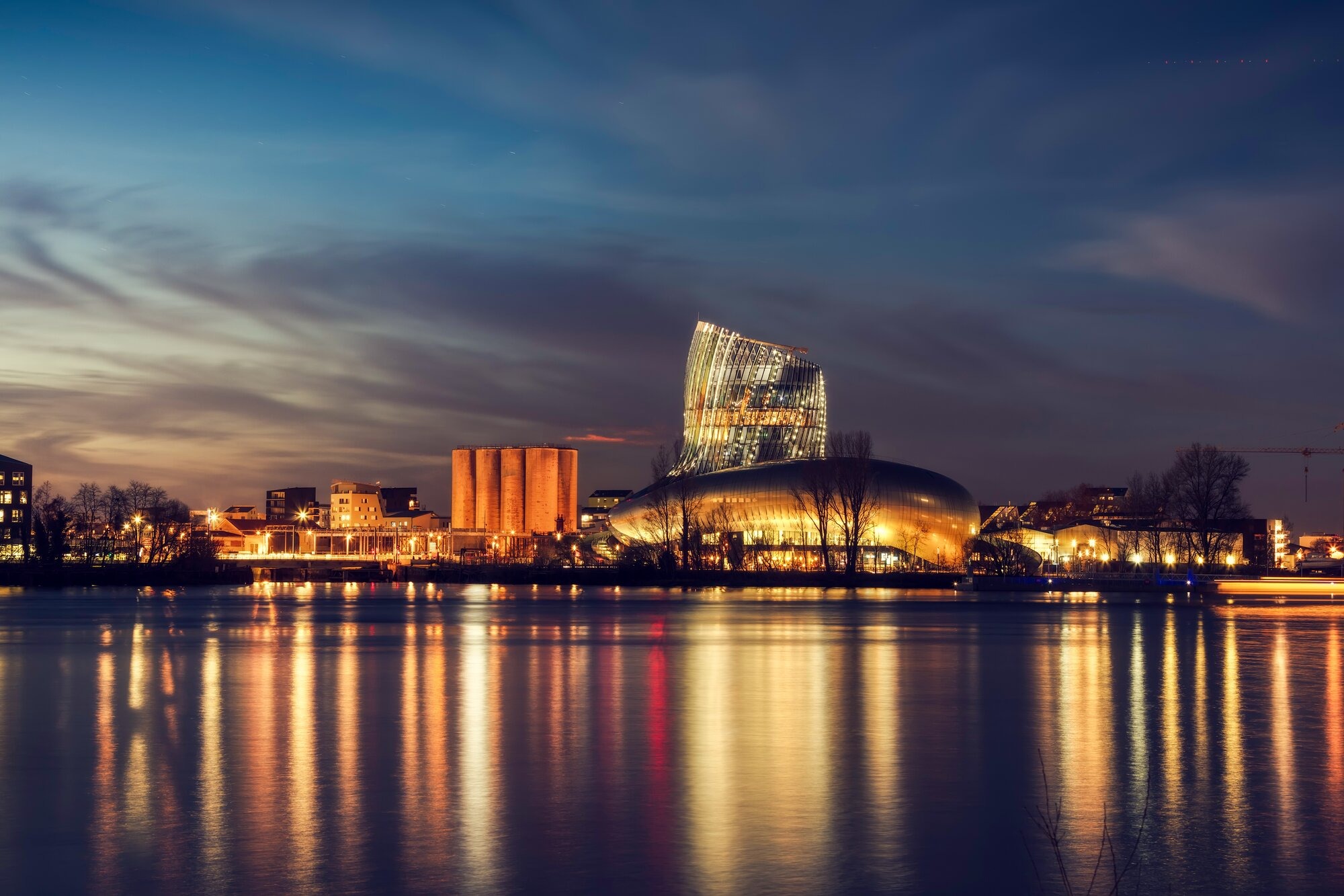 Illuminated Modern Architecture Along the Garonne River at Dusk A stunning twilight view of contemporary riverside architecture and cultural buildings reflected