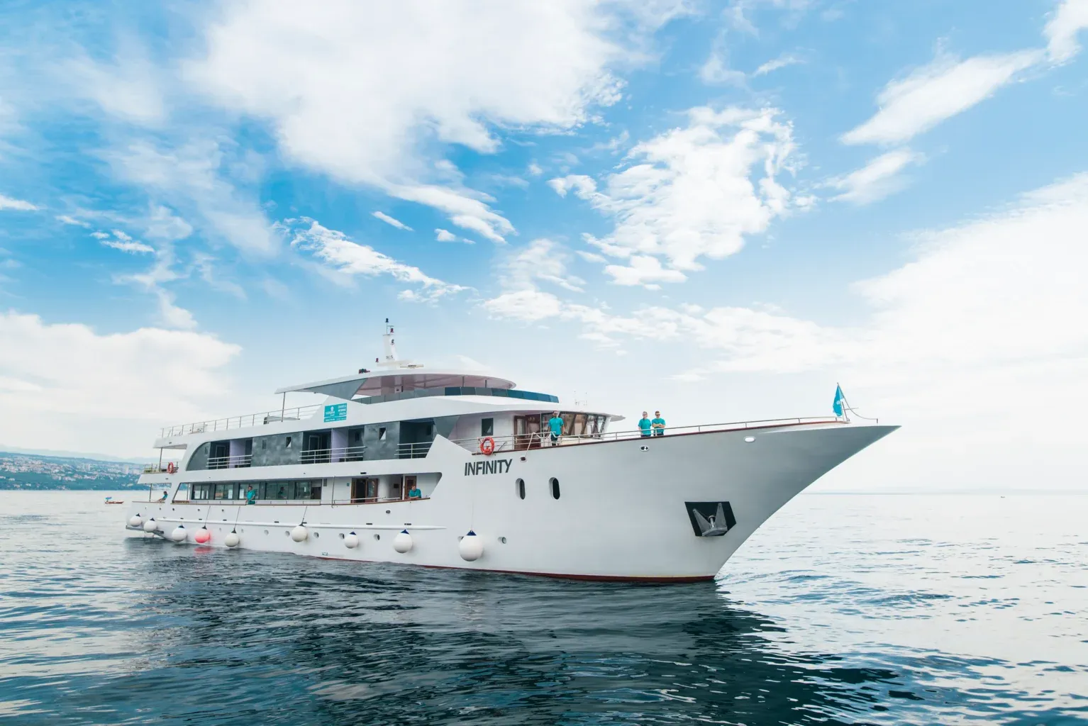 Infinity Luxury Cruise Ship in Calm Waters A multi-deck luxury cruise ship named Infinity anchored in calm blue waters under a bright sky