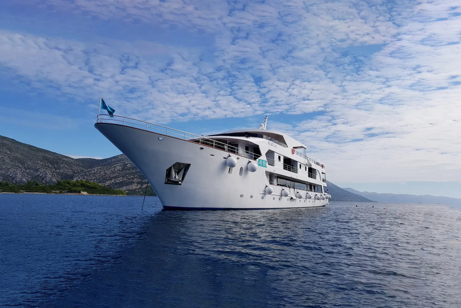 Katarina Line Cruise Ship Anchored in Mediterranean Waters A white multi-deck expedition cruise ship anchored in clear blue Mediterranean waters with dramatic