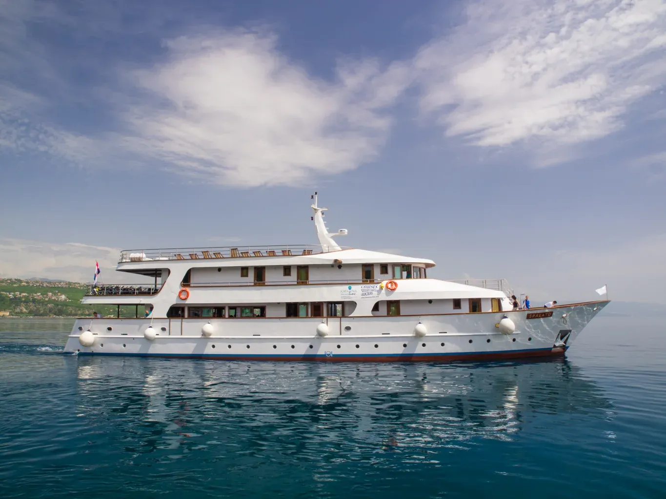 Katarina Line Cruise Ship in Mediterranean Waters A luxurious multi-deck cruise ship painted in white with a blue hull stripe, anchored in calm