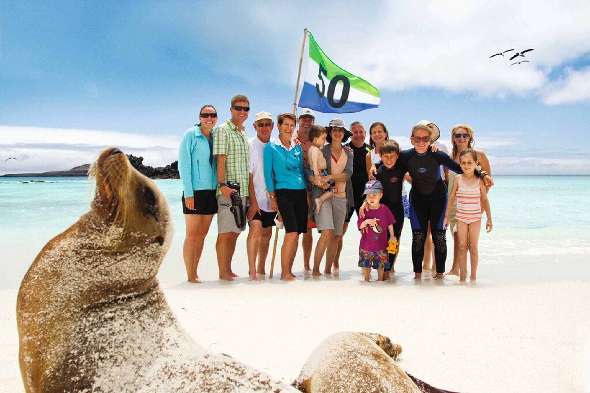 Lindblad Expedition Group with Galápagos Sea Lion A group of passengers and crew from a Lindblad Expeditions-National Geographic expedition pose on