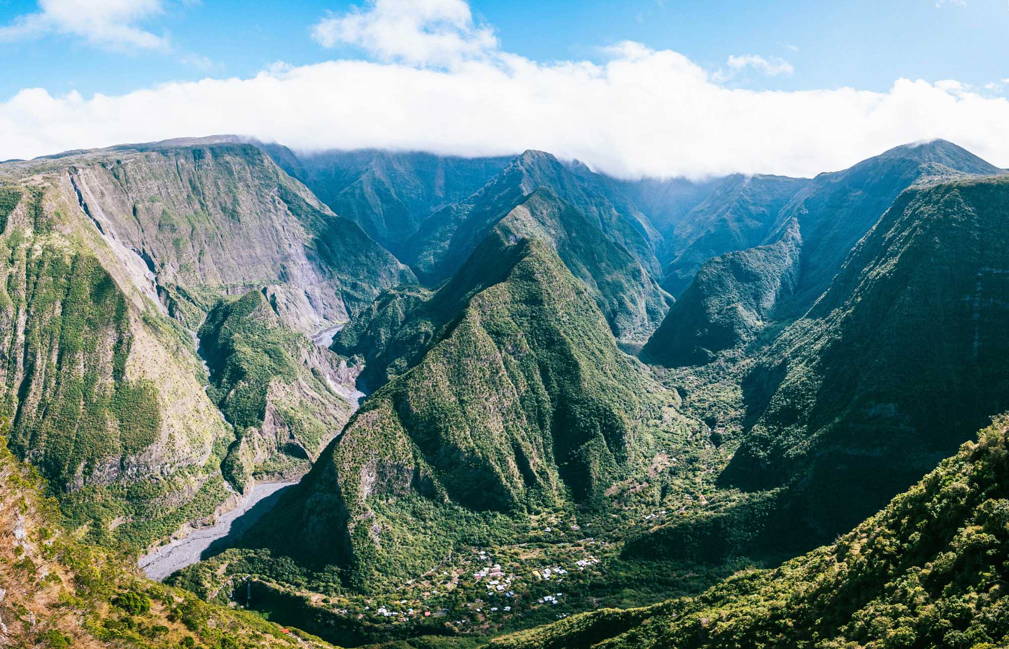 Lush Valley with River and Dramatic Cliffs A breathtaking aerial view of a verdant valley carved by a winding river, surrounded by steep