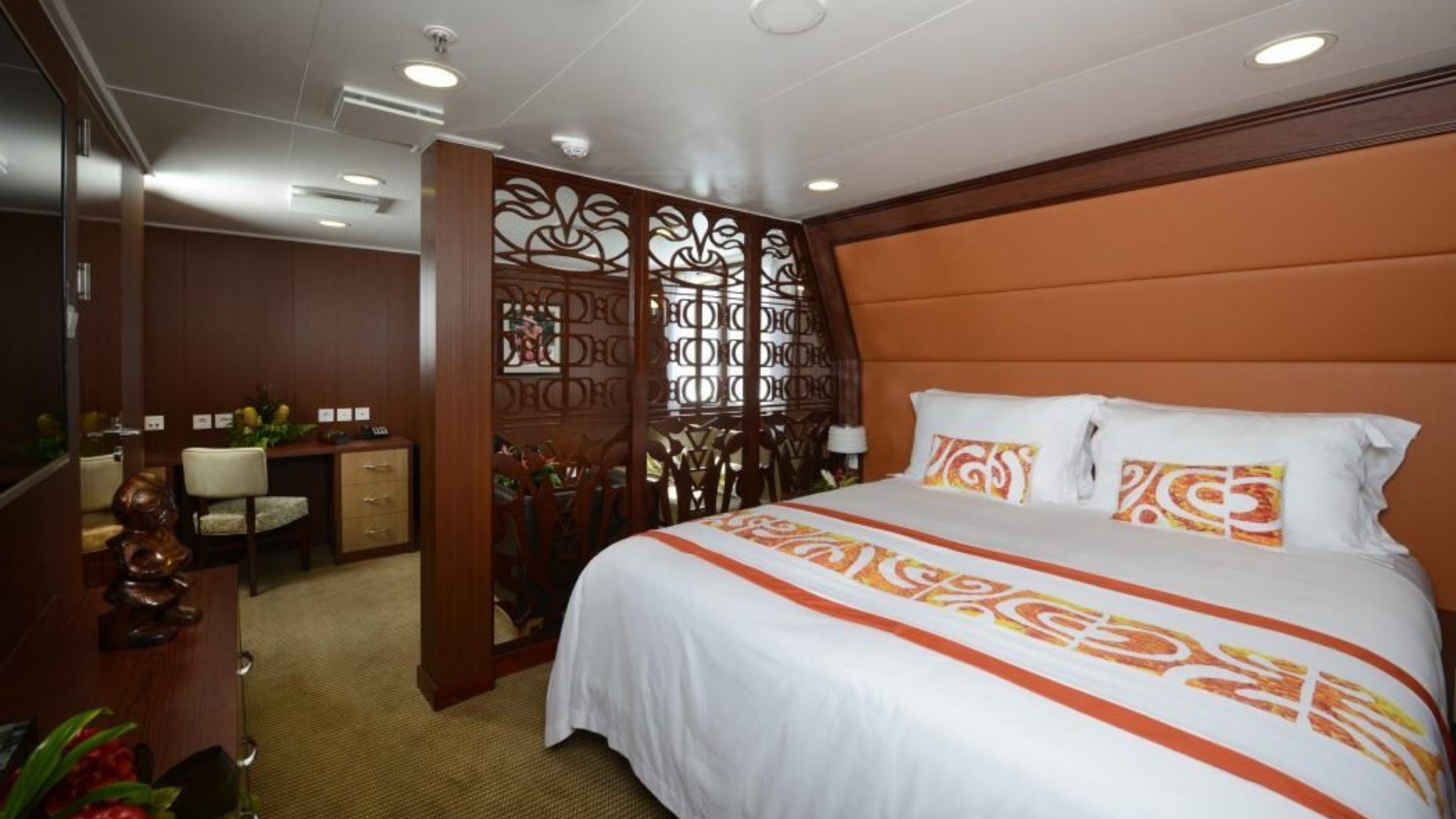 Luxury Cruise Ship Stateroom with Orange Accents An elegantly appointed suite aboard a cruise ship featuring a queen-sized bed with orange and white