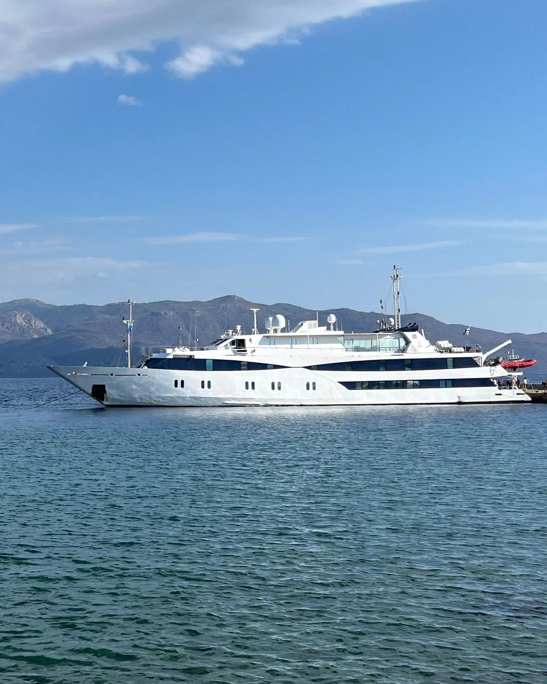 A sleek white luxury expedition yacht with distinctive porthole windows and modern design anchored