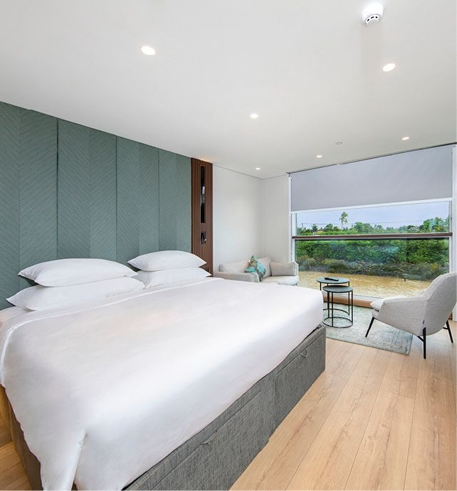 Luxury Panorama Balcony Suite with River View A modern, spacious suite featuring a king-size bed with white linens, a teal-green quilted