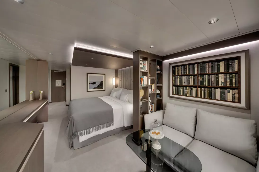 Luxury Suite Cabin with Library and Seating A sophisticated, modern luxury cruise ship suite featuring a king bed with crisp white linens