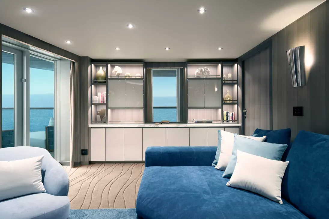 Luxury Suite with Ocean View Balcony A modern luxury cruise ship suite featuring a king-size bed with blue upholstery, floor-to-ceiling