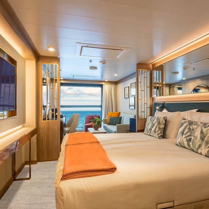 Luxury Suite with Ocean View on Expedition Vessel A spacious and elegantly appointed suite aboard an expedition cruise ship, featuring a king-size