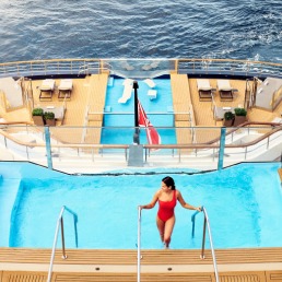 Luxury Yacht Pool Deck at Sea An overhead view of an elegant swimming pool aboard a luxury yacht, featuring a solitary guest