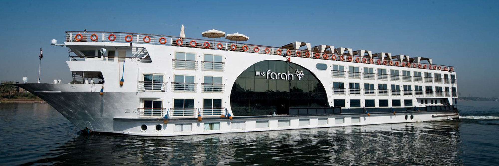 M/S Farah Nile River Cruise Ship Exterior The M/S Farah, a modern multi-deck river cruise ship, is moored on the Nile River. The white vessel
