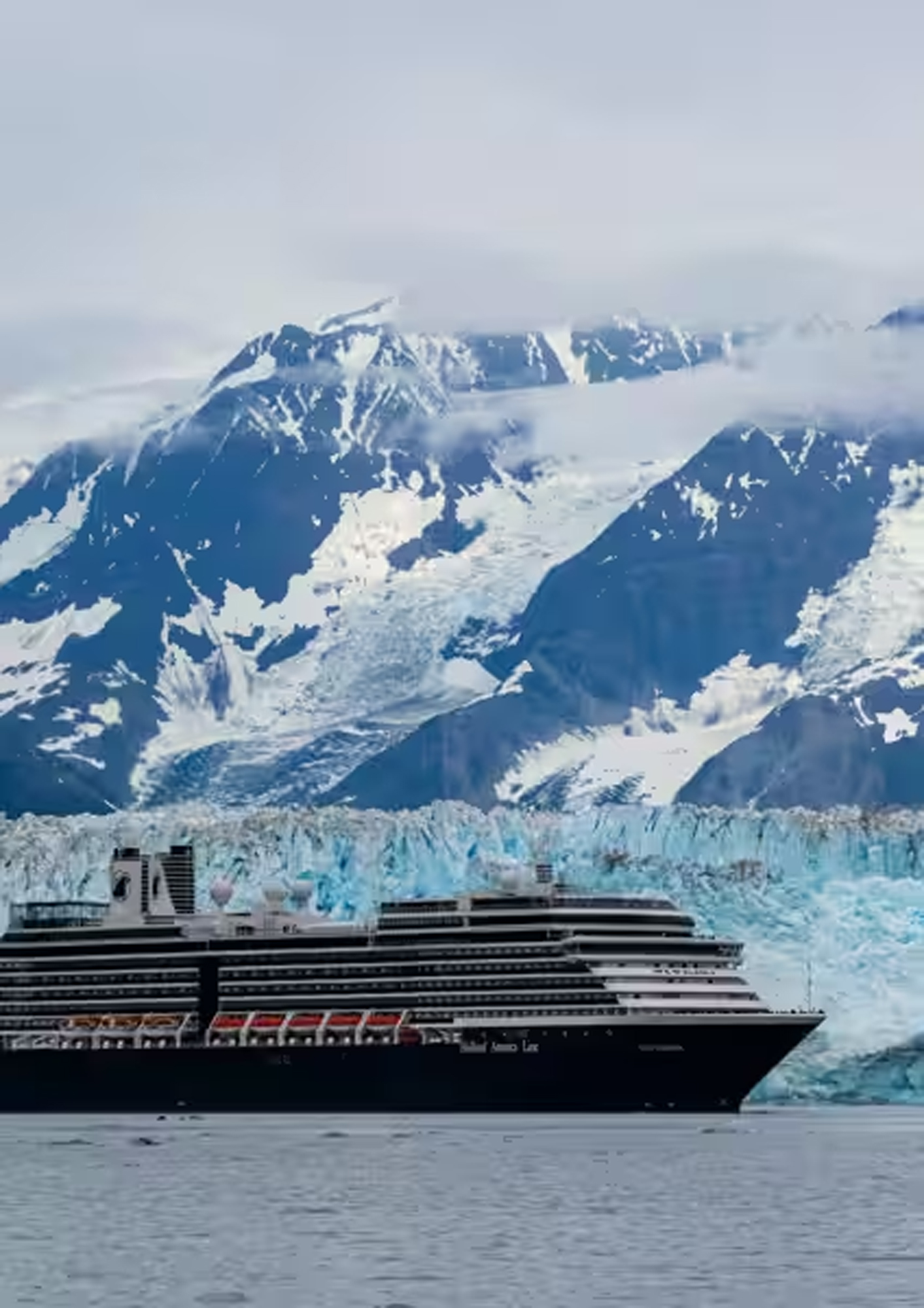 A large Holland America Line cruise ship navigates near the magnificent Hubbard Glacier in Alaska