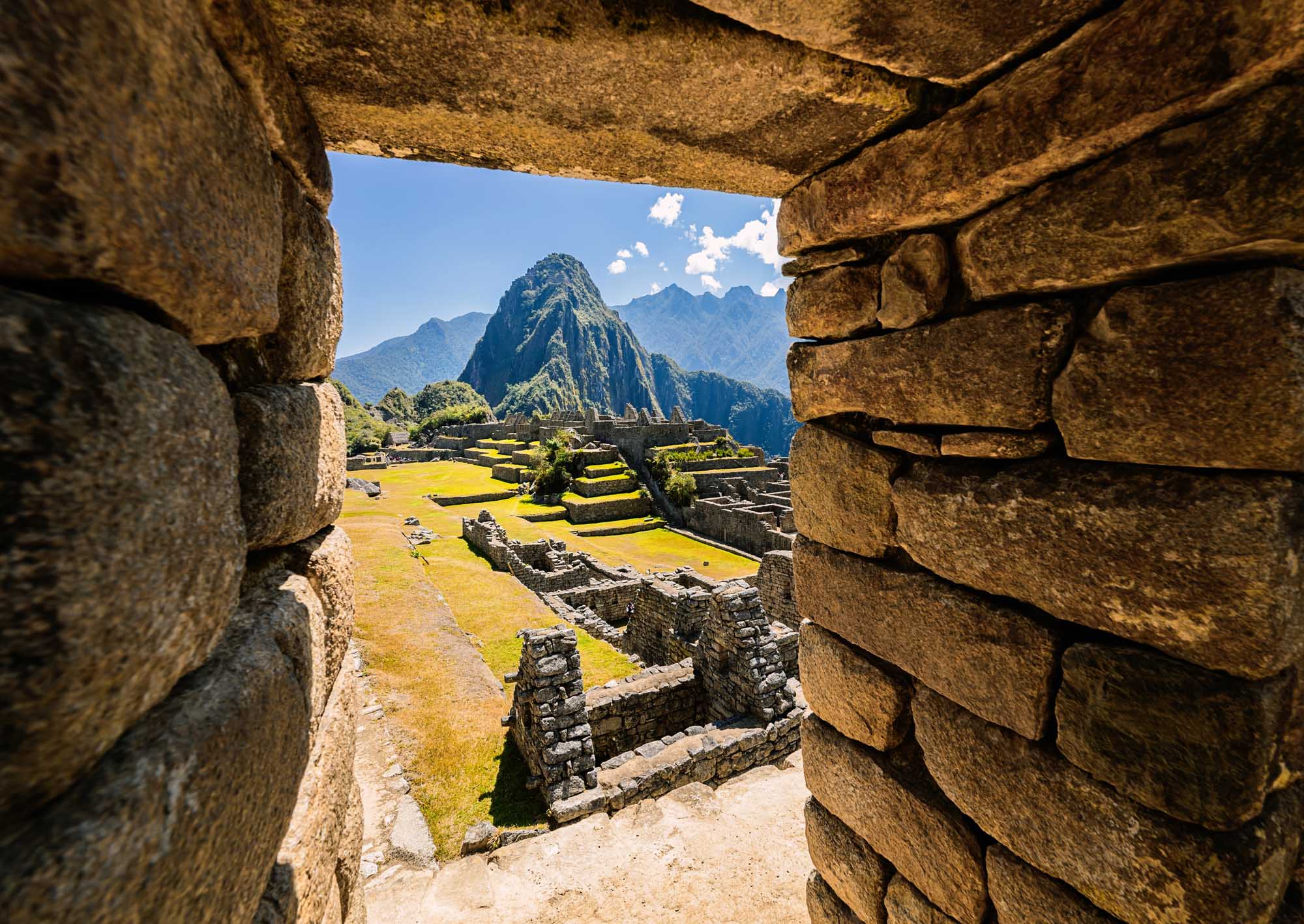 Machu Picchu Through Ancient Stone Doorway A breathtaking view of Machu Picchu's iconic mountain peak and terraced ruins framed through