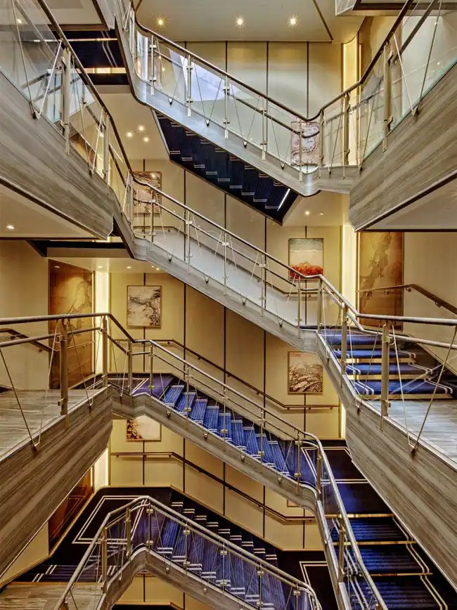 Multi-Level Atrium with Modern Staircase Design A striking multi-story atrium aboard a luxury cruise ship featuring contemporary staircases