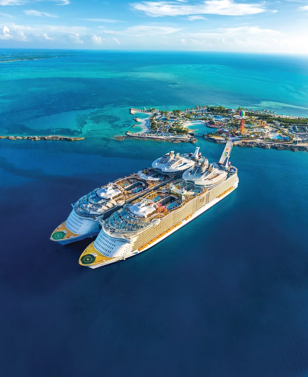 Navigator of the Seas Docked at Perfect Day Coco Cay An aerial view of a massive Royal Caribbean cruise ship docked at the company's private island