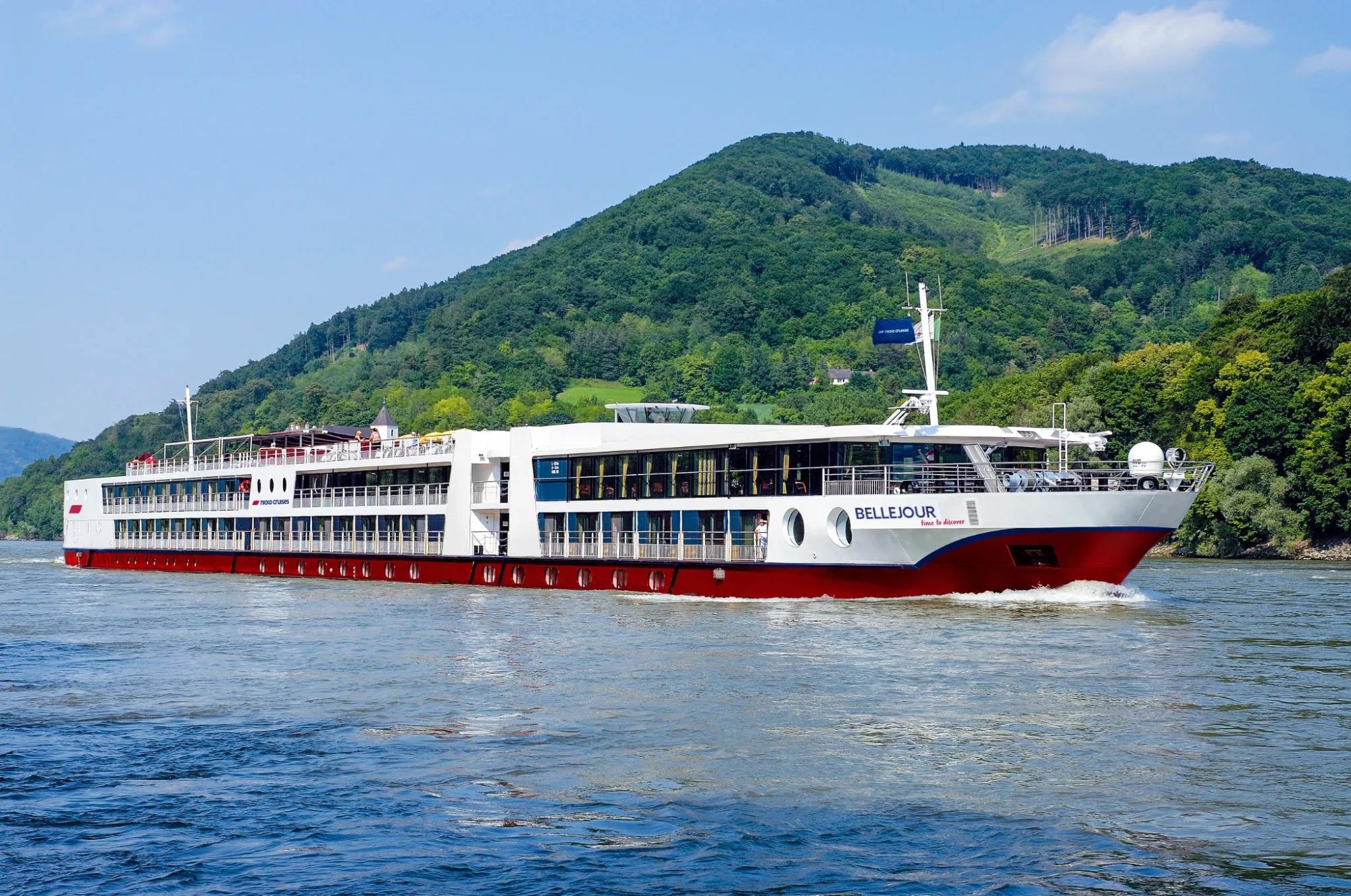 A modern river cruise ship with white and red hull, multi-deck passenger accommodations