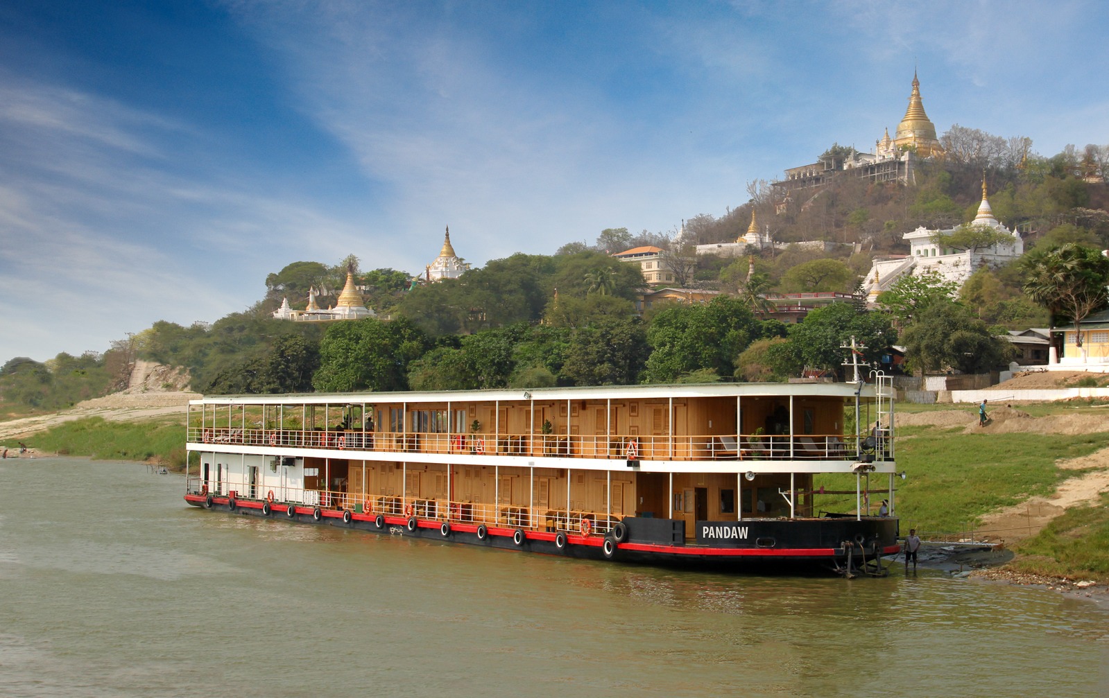 A two-deck wooden river cruise vessel named Pandaw moored on the muddy waters of the Irrawaddy