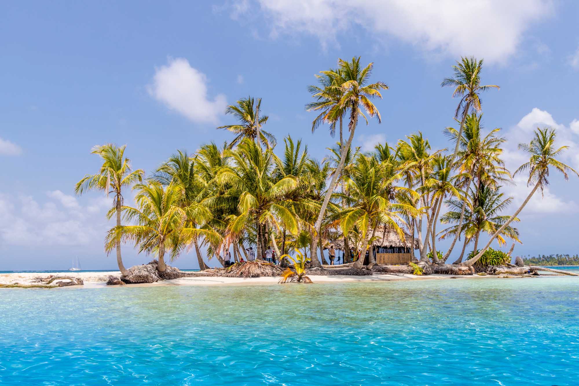 Pelicano Island in Panama’s San Blas Islands A pristine tropical island dotted with coconut palms and traditional structures, surrounded