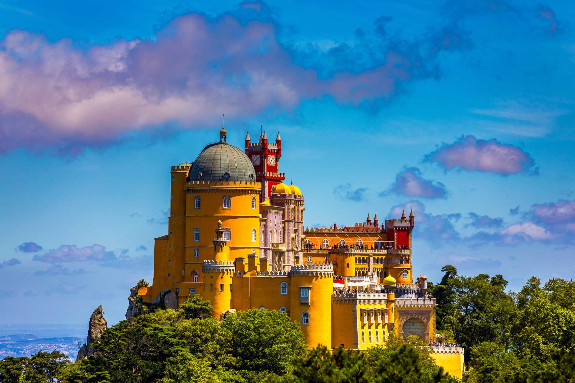Pena Palace in Sintra, Portugal A stunning panoramic view of the iconic Pena National Palace perched atop a forested hilltop