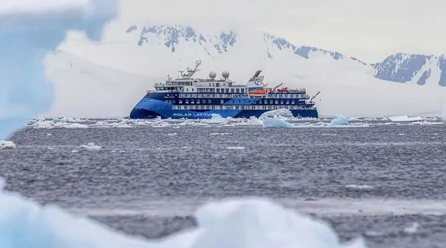 The Polar Latitudes expedition cruise ship navigates through icy Antarctic waters with snow-capped