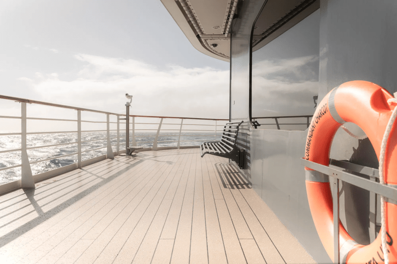Ponant Expedition Ship Deck with Life Ring The upper deck of a Ponant expedition cruise vessel overlooking the open ocean, featuring a wooden