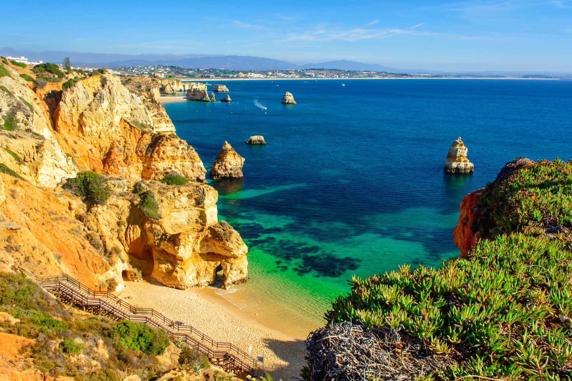 Praia do Camilo Beach, Ponta da Piedade, Algarve A stunning coastal view of Praia do Camilo beach featuring golden sandstone cliffs, crystal-clear