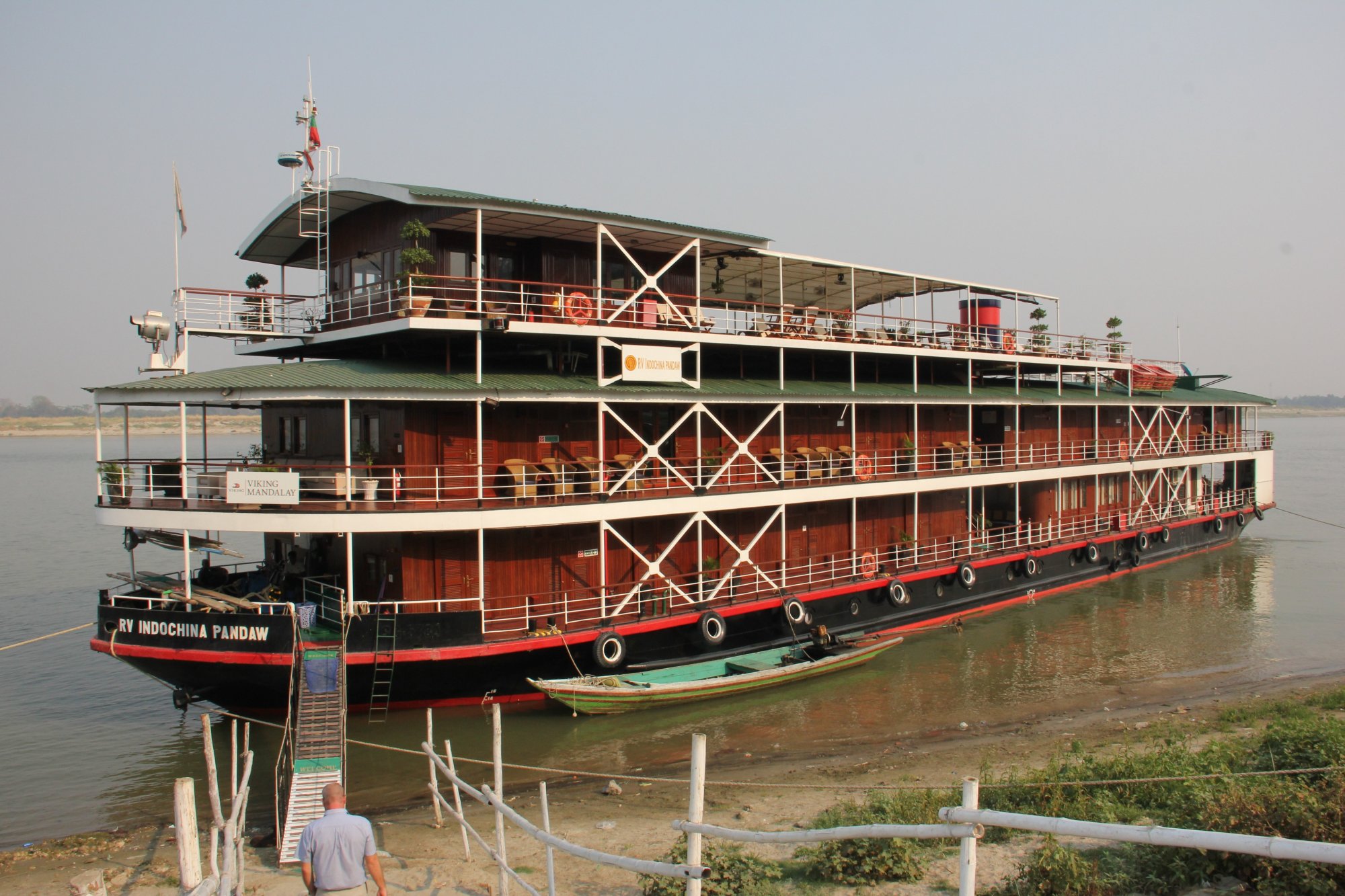 RV Indochina Pandaw River Cruise Ship A striking three-deck river cruise vessel named RV Indochina Pandaw docked along a riverbank