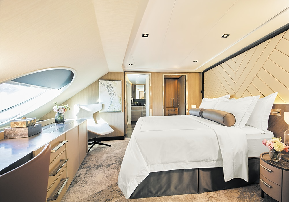 A luxurious suite bedroom aboard Regent Seven Seas Cruises featuring a king bed with white linens