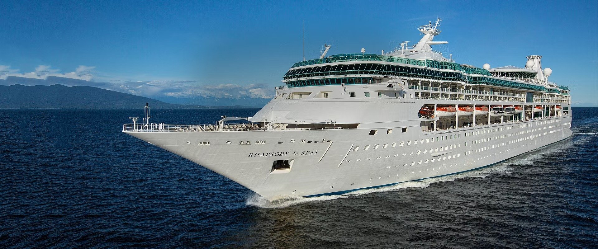 Rhapsody of the Seas Cruising in Alaska A magnificent large cruise ship, the Rhapsody of the Seas, sails through deep blue waters