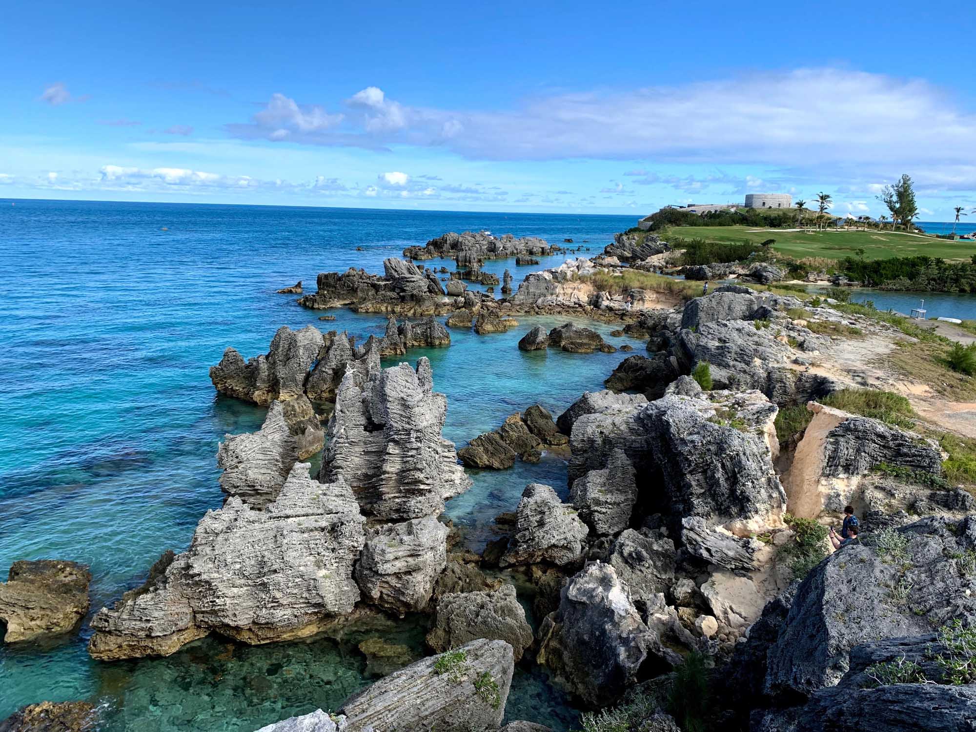 Rocky Coastal Cliffs and Turquoise Waters in Bermuda A scenic coastal landscape featuring dramatic limestone rock formations jutting into crystal-clear