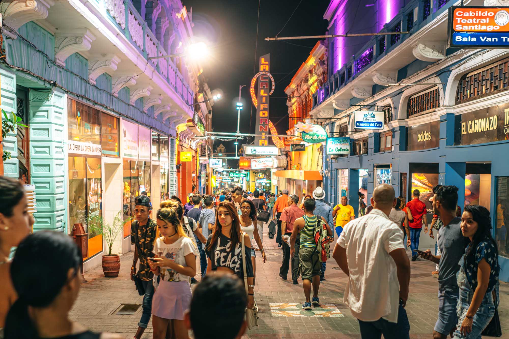 Santiago de Cuba Evening Street Scene A vibrant nighttime street scene in Santiago de Cuba filled with locals and shoppers beneath