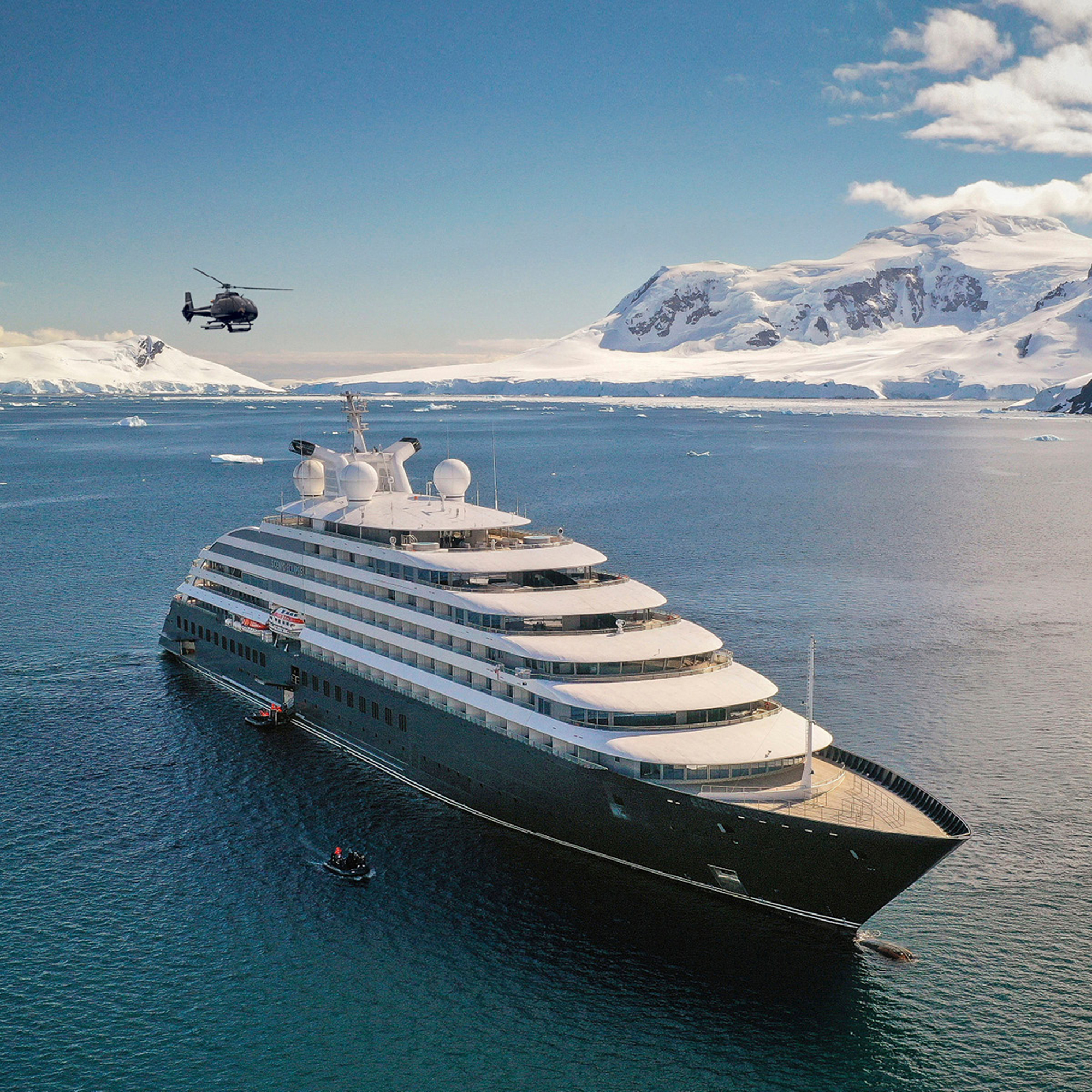 A luxury expedition cruise ship anchored in pristine Antarctic waters surrounded by massive