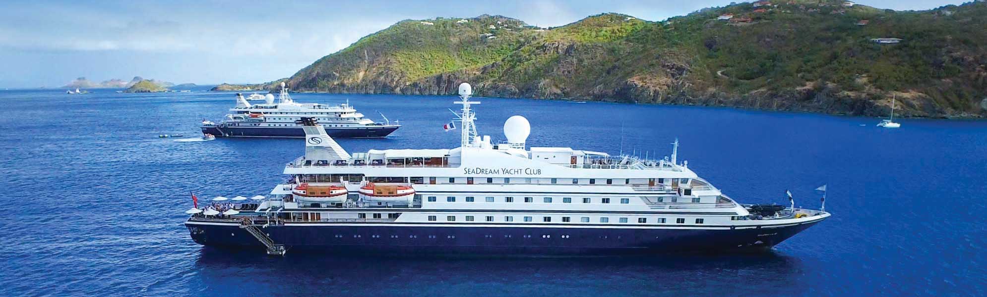 SeaDream Yacht Club Anchored in Tropical Waters The luxury expedition yacht SeaDream Yacht Club is anchored in crystalline blue waters near a lush