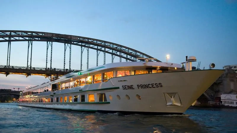 Seine Princess River Cruise Ship at Dusk The Seine Princess, an elegant river cruise ship, is illuminated at dusk as it passes beneath