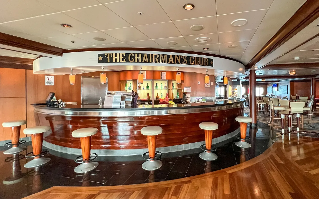 The Chairman’s Club Bar aboard Cordelia An elegant curved bar lounge aboard the Cordelia cruise ship, featuring a distinctive mahogany