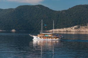 Traditional Gulet Sailing Vessel in Mediterranean Waters A classic wooden gulet sailing vessel with two masts anchors in calm, crystal-clear Mediterranean