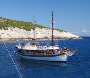 Traditional Sailing Vessel in Mediterranean Waters A classic wooden sailing ship with two tall masts anchored in crystal-clear turquoise waters