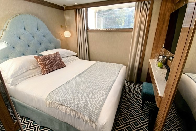 Uniworld River Cruise Ship Cabin with Blue Headboard A luxurious stateroom aboard a Uniworld river cruise ship, featuring a plush light blue tufted